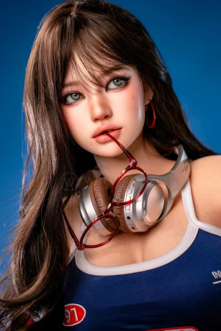 Face close-up of Hanae, a 161cm realistic companion doll, with silver headphones around her neck and red glasses held lightly between her lips.
