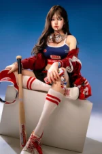 Hanae, a 161cm realistic sex doll, sits cross-legged on the white cube with silver headphones at her neck, a red phone in hand, and the baseball bat upright beside her.