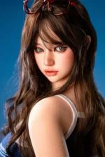 Close portrait of Hanae, a 161cm silicone companion doll, looking back over one shoulder with red glasses resting on top of her dark hair.