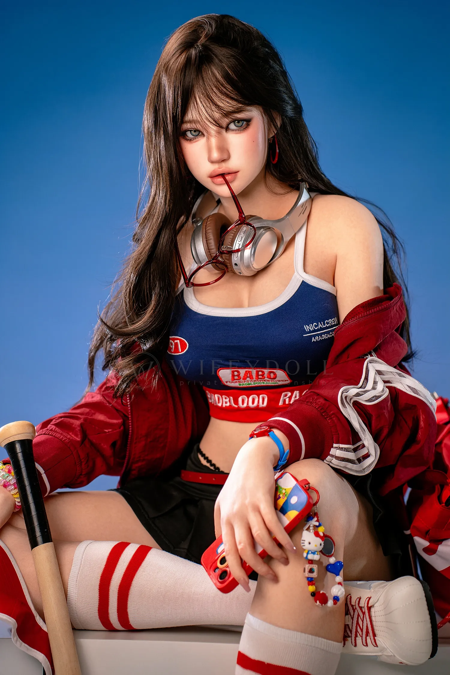 Hanae, a 161cm silicone companion doll, sits on a white cube with silver headphones around her neck, a red phone in one hand, and a baseball bat beside her.