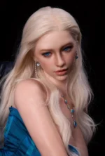 Lottie lowers her gaze slightly, platinum-blonde hair falling past crystal earrings above the blue gemstone necklace and teal dress.