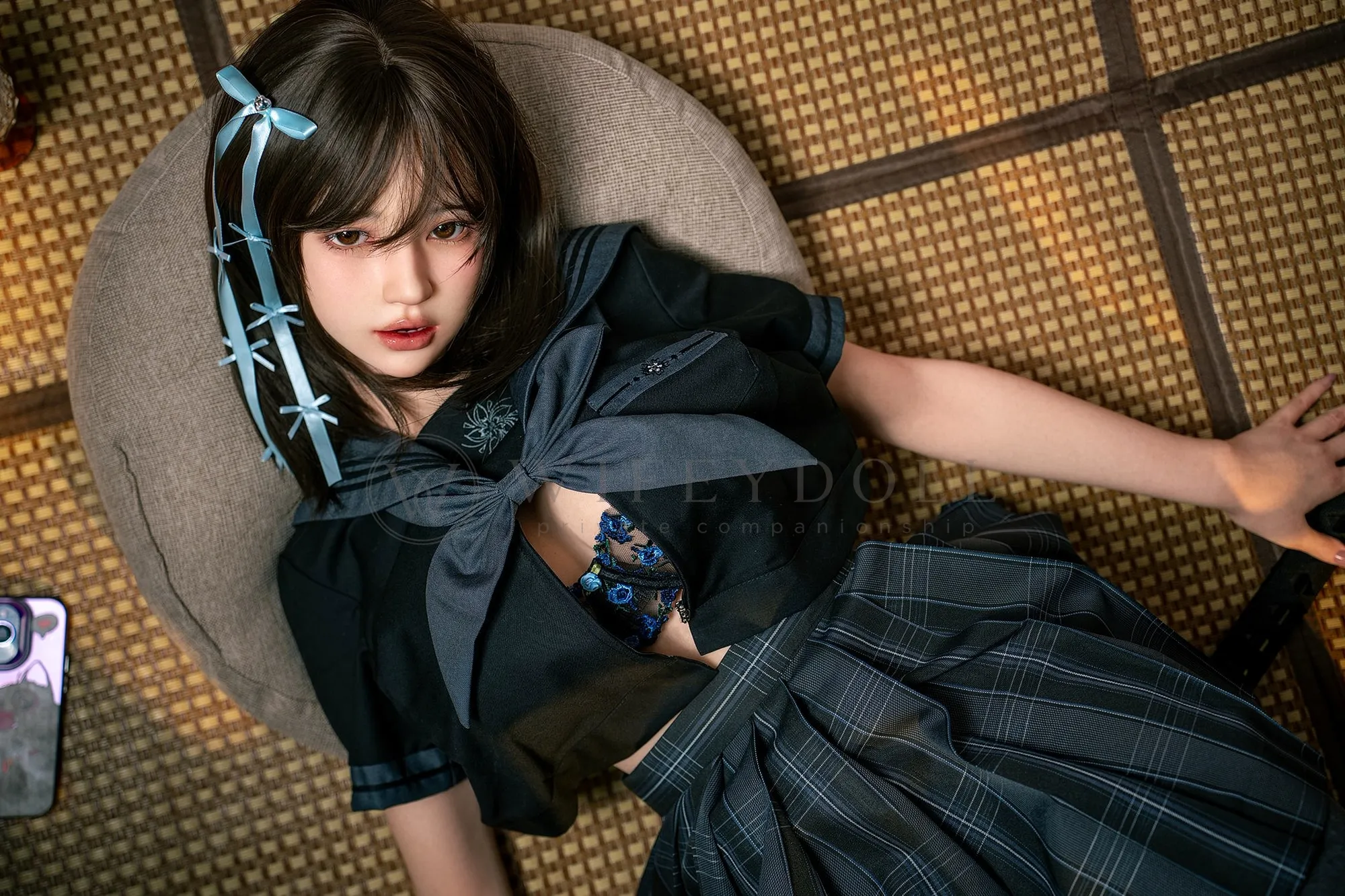 Mika, a 161cm silicone companion doll, reclining on a round cushion with the navy top open over a blue lace bra.