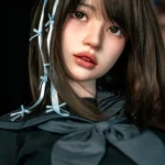 Face close-up of Mika, a 161cm silicone sex doll, with dark bangs, blue hair ribbons, and soft pink lips.