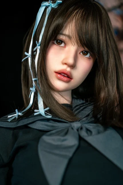 Face close-up of Mika, a 161cm silicone sex doll, with dark bangs, blue hair ribbons, and soft pink lips.