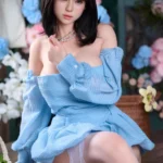 Upper-body portrait of Mina, a realistic silicone doll in a blue off-shoulder dress.
