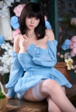 Upper-body portrait of Mina, a realistic silicone doll in a blue off-shoulder dress.