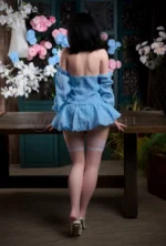 Mina full-body silicone sex doll standing from the back in a blue off-shoulder dress.