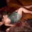 Rosa stretches out on the patterned rug in a green sequin dress, her knees near the sofa and chestnut hair spread across the rug.