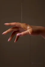 A posed silicone doll hand shows the even glossy finish created by applied lubricant.