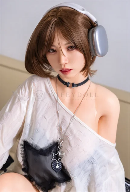 Close portrait of Suki in silver headphones and a black choker, with her white sweater slipped low on one shoulder.