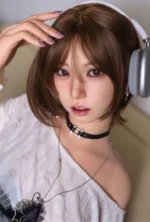 Close-up of Suki with silver headphones over her short brown bob, one hand resting lightly across the top of her hair.