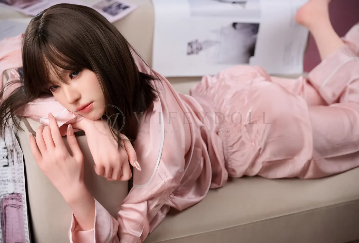 Viki Asian silicone doll reclining front-facing on a white sofa.