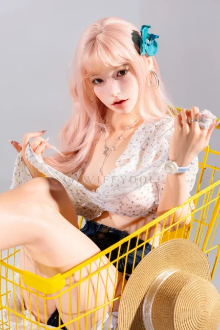 Mio, a 166cm realistic silicone doll, sits inside the cart holding a yellow straw near her face.