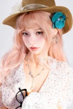Close-up portrait of Mio as she appears in a close-up beneath a straw hat with a turquoise flower.