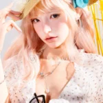 Upper-body portrait of Mio as she poses beneath a straw hat with a turquoise flower and soft pink hair.
