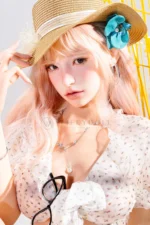 Upper-body portrait of Mio as she poses beneath a straw hat with a turquoise flower and soft pink hair.