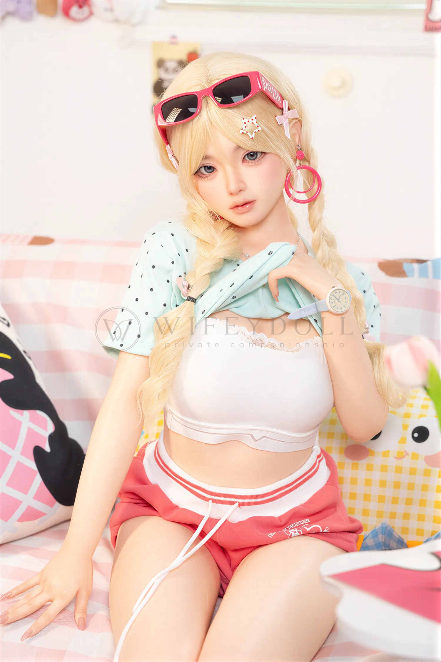 Xia Ying silicone companion doll seated on a pink bed wearing a white top and red shorts.