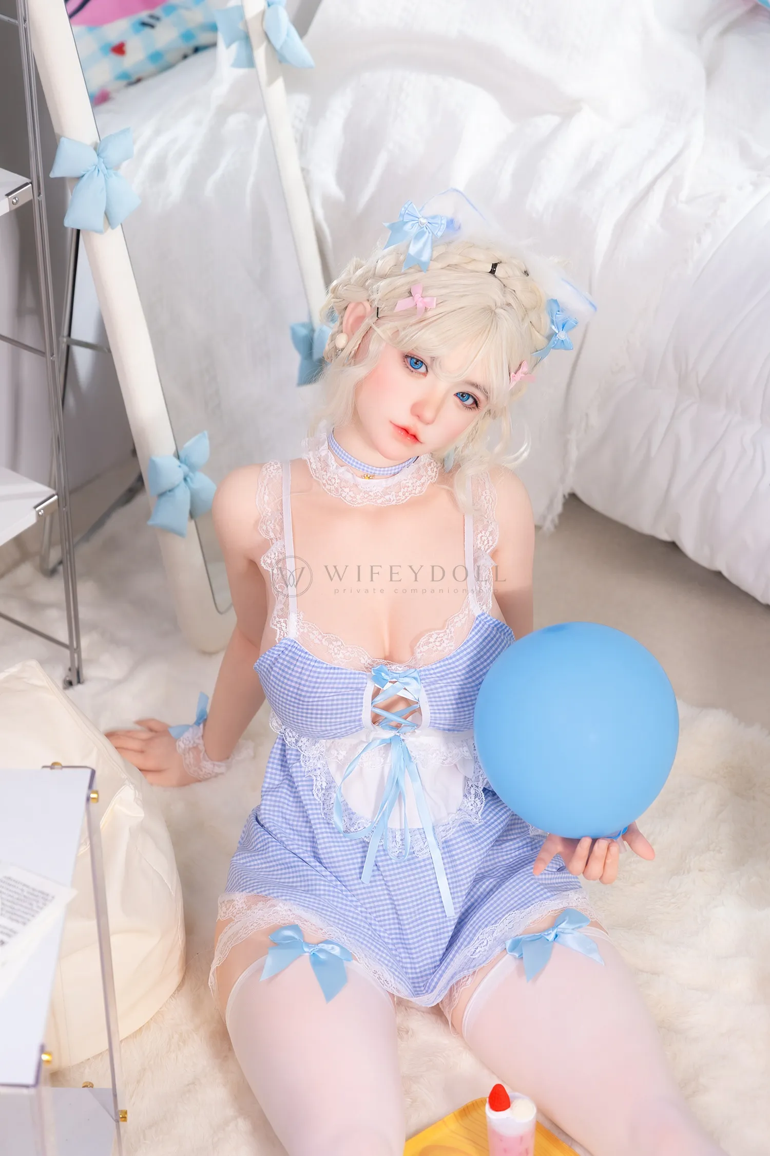 Zia, a 154cm companion doll, sits on the white rug holding a blue balloon beside the bed.