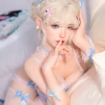 Zia, a 154cm companion doll, rests one hand at her cheek beside the cream cushion in a close portrait.
