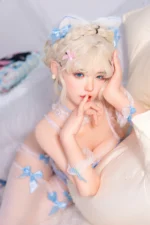 Zia, a 154cm companion doll, rests one hand at her cheek beside the cream cushion in a close portrait.