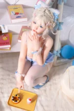 Zia, a 154cm companion doll, kneels on the rug and reaches toward the yellow tray, the fruit tart and pink drink set just in front of her.