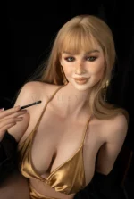 Upper-body detail of a doll wearing a glossy gold bikini.