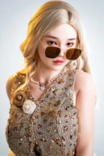Vivienne realistic silicone sex doll looking over sunglasses in a top decorated with flowers and beadwork.