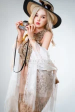 Wide portrait of Vivienne silicone doll in a long lace shawl, holding a camera at her cheek.